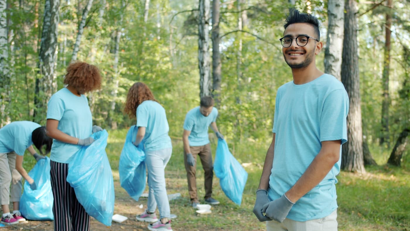 Student volunteers collecting waste together outdoors with collection bags